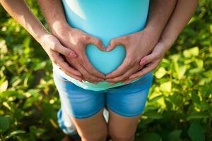 man's handen omhelzing een buik van de zwanger vrouw foto