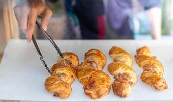 vrouw hand- zetten croissants Aan een houten dienblad bereiden voor verkopen Bij de bakkerij winkel. foto