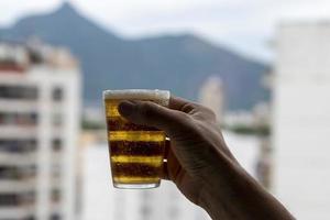 Mens Holding glas van bier Aan wazig stedelijk stad achtergrond foto