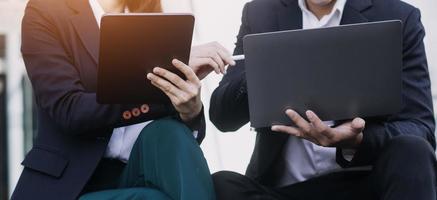 Aziatisch bedrijf Mens en jong mooi vrouw werken Aan digitaal tablet computer staand buiten kantoor gebouw. foto