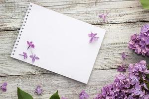 schoon kladblok met voorjaar lila bloemen Aan wit houten achtergrond foto