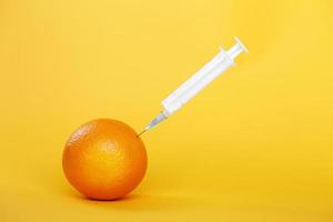 oranje fruit met injectiespuit extraheren vloeistof met vitamine c. natuurlijk anti veroudering schoonheidsmiddelen concept foto