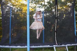 weinig kind meisje jumping Aan de trampoline in de terug werf foto