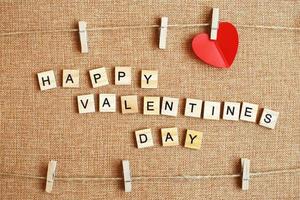 opschrift gelukkig Valentijnsdag dag met harten Aan kleren pin Aan bruin textiel achtergrond foto