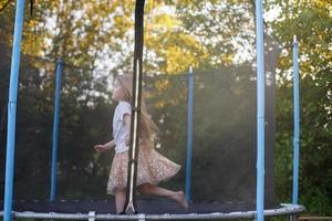 weinig kind meisje jumping Aan de trampoline in de terug werf foto