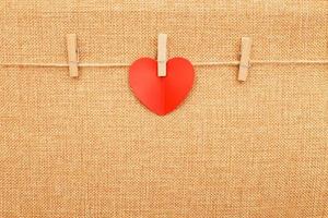 rood hart Aan kleren pin Aan bruin textiel achtergrond foto