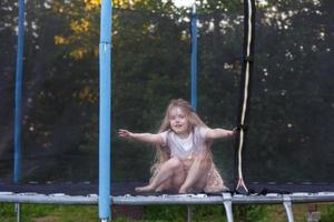 weinig kind meisje jumping Aan de trampoline in de terug werf foto