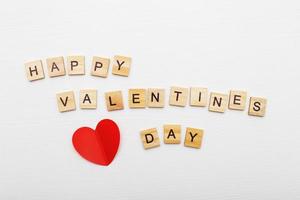 opschrift gelukkig Valentijnsdag dag met een rood harten Aan een wit houten achtergrond. foto