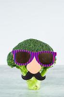 grappig schattig groenten broccoli. broccoli met papier snor en bril. gezond voedsel concept foto