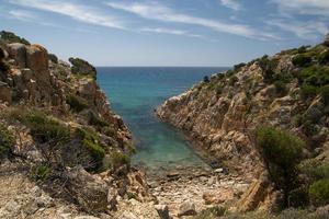 een turkoois blauw zee en wit zand strand met rotsen in Sardinië Italië foto