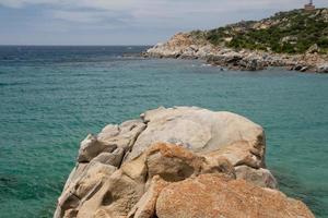 een turkoois blauw zee en wit zand strand met rotsen in Sardinië Italië foto