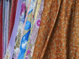 kleurrijk wijnoogst sjaals met verschillend patronen, kleuren en texturen hangende Aan een rek Bij een buitenshuis winkel foto
