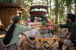 groep toeristen vrienden camping en hebben een barbecue en drinken bier-alcohol en Botsing een bier fles met de partij samen met genot en geluk in zomer foto