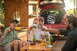 groep toeristen vrienden camping en hebben een barbecue en drinken bier-alcohol met partij samen met genot en geluk in zomer foto