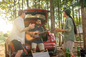 groep toeristen drinken bier-alcohol en Speel gitaar samen met genieten en geluk in zomer terwijl camping foto