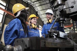 industrieel arbeiders team in beschermend en veiligheid uniformen, mannetje manager, en vrouw collega's gelukkig werk met metaalwerk machines in fabricage fabriek. professioneel mechanisch productie ingenieur. foto