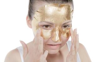 vrouw goud masker, mooi model- met gouden huid kunstmatig, schoonheid huidsverzorging en behandeling foto