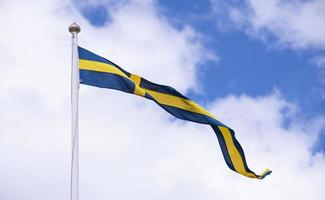 Zweeds vlag tegen blauw lucht met wit wolken. foto