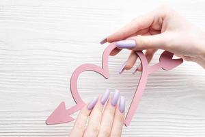 meisjes handen met delicaat Purper manicure en versieren hart foto