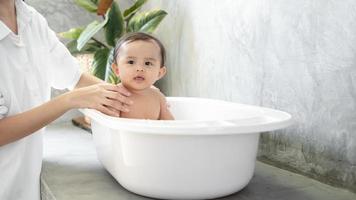 aanbiddelijk baby meisje nemen een bad met moeder, familie, kind, kinderjaren en ouderschap concept foto