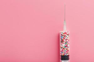 medisch injectiespuit gevulde met kleurrijk ballonnen Aan een roze achtergrond met vrij ruimte. foto