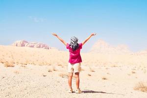 gelukkig blij vrouw toerist staan met handen omhoog Aan wadi rum woestijn Aan wandeltocht Aan vakantie vakantie in wadi rum. populair wadi rum woestijn in Jordanië foto