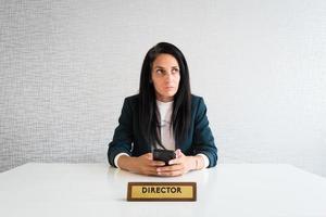 jong Kaukasisch brunette bedrijf vrouw regisseur in kantoor attent ondernemer houden telefoon maken beslissingen denken voordat tekst r bespotten omhoog geïsoleerd foto