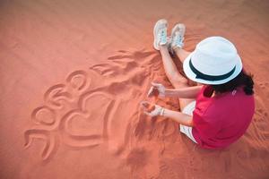 mooi jong vrouw spelen met zand Aan een zand duin van wadi rum woestijn, ook gebeld de wally van de maan, van Jordanië. vakantie in Jordanië. foto