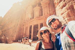 jong knap paar opgewonden nemen selfie in petra door schatkist mijlpaal. reislustig Mens en vrouw, glimlachen en op zoek Bij camera. reis, geluk en levensstijl concepten. foto