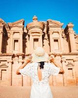 filmische petra achtergrond Kaukasisch jong vrouw in wit jurk en hoed genieten van petra een'deir klooster, van petra grootste monument, UNESCO wereld erfgoed plaats, Jordanië. foto