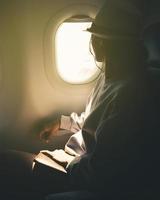 dichtbij omhoog silhouet van Kaukasisch vrouw looks uit de venster van een vliegend vliegtuig. passagier Aan de vlak resting naast de venster foto