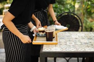serveerster met schort portie bevroren koffie naar klant Bij cafe. foto