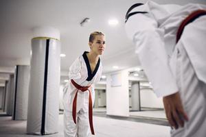 krijgshaftig artiest met onbekwaamheid groet haar spaarzaam partner voordat de strijd gedurende taekwondo opleiding in Gezondheid club. foto