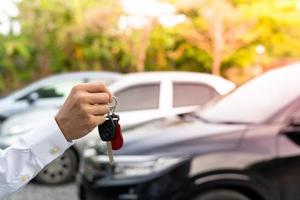 verkoop auto, auto uitverkoop, transactie concept de handelaar geeft de auto sleutels naar de nieuw eigenaar of huurder met een verzekering contract. foto