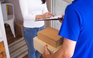 de vrouw is ondertekening de naam van de levering personeel verzonden naar de voorkant deur. foto