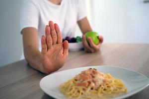 een vrouw is controlerend gewicht Kiezen naar eten appels en groenten. foto