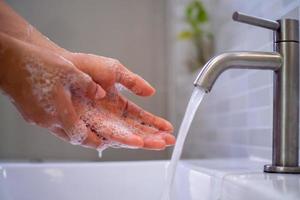 wassen uw handen met zeep, voorkomen virus en bacterie in de kraan met rennen water. mooi zo hygiëne voordat aan het eten of behandeling openbaar items foto