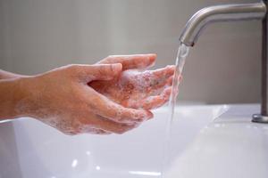 wassen uw handen met zeep, voorkomen virus en bacterie in de kraan met rennen water. mooi zo hygiëne voordat aan het eten of behandeling openbaar items foto