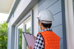 een inspecteur of ingenieur is inspecteren en inspecteren een gebouw of huis gebruik makend van een controlelijst. ingenieurs en architecten werk naar bouwen de huis voordat overhandigen het over- naar de huiseigenaar. foto