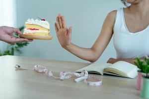 handen stuurt bord van taart naar slank Dames. de vrouw geduwd de bord de taart en geweigerd naar eten snoepgoed en dik. mensen Gezondheid zorg en eetpatroon concept foto