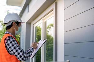 een inspecteur of ingenieur is inspecteren en inspecteren een gebouw of huis gebruik makend van een controlelijst. ingenieurs en architecten werk naar bouwen de huis voordat overhandigen het over- naar de huiseigenaar. foto