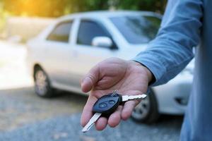 de auto eigenaar is staand de auto sleutels naar de koper. gebruikt auto verkoop foto