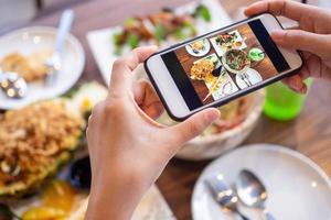 de meisjes hand- is nemen afbeeldingen van de voedsel Aan de tafel Bij huis na bestellen voedsel online naar eten Bij huis. de concept van mobiel telefoons naar bestellen voedsel online foto