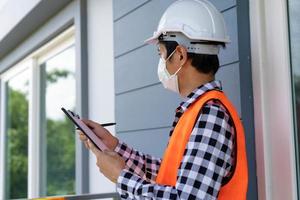 een inspecteur of ingenieur is inspecteren en inspecteren een gebouw of huis gebruik makend van een controlelijst. ingenieurs en architecten werk naar bouwen de huis voordat overhandigen het over- naar de huiseigenaar. foto