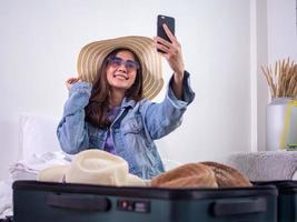 de meisjes zijn opgewonden over kiezen een hoed naar slijtage Aan vakantie. zittend en verzamelen kleren in Tassen naar bereiden naar reizen gelukkig. foto