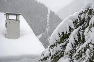 schoorsteen van berg huis gedekt door sneeuw in dolomieten foto