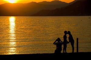 Mens en vrouw terwijl zoenen Aan sestri levante strand Bij zonsondergang foto