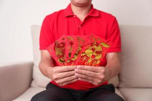 Mens Holding Chinese rood envelop met gouden konijn en zegen woord, geld geschenk voor gelukkig maan- nieuw jaar vakantie. Chinese zin middelen geluk, gezond, Lucky en rijk foto