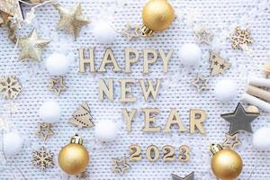 gelukkig nieuw jaar houten brieven en de getallen 2023 Aan feestelijk wit gebreid achtergrond met pailletten, sterren, lichten van slingers. hartelijk groeten, ansichtkaart. kalender, Hoes foto