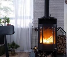 zwart fornuis, haard in interieur van huis in zolder stijl. alternatief milieuvriendelijk verwarming, warm knus kamer Bij huis, brandend hout foto